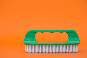 Green cleaning brush on orange background. Copy, empty space for text