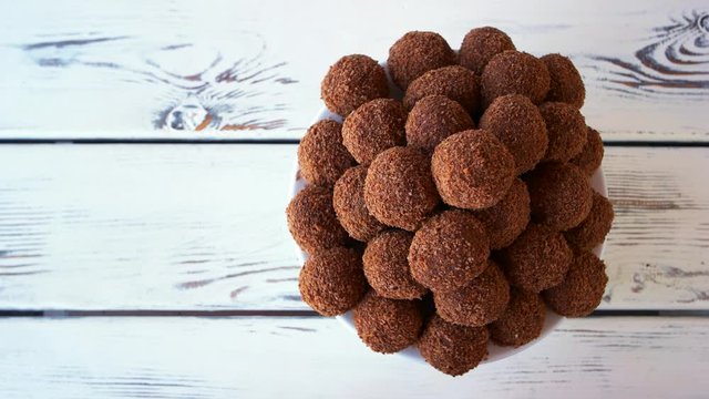 Pile of dark ball shaped sweets. Ball shaped creamy candies, top view. Candies with crumbs. Luxury dessert with smooth chocolate.