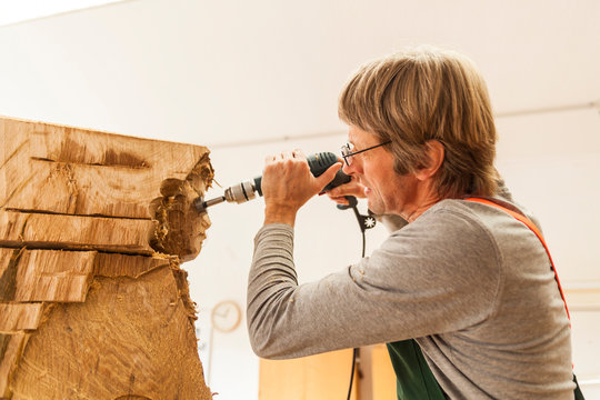Wood carver in workshop working on sculpture with milling machine
