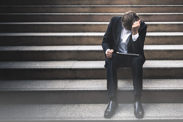 Businessmen wear a black suit, sitting on concrete stairs, being stressed Because of business problems And unsuccessful, to employee concept.