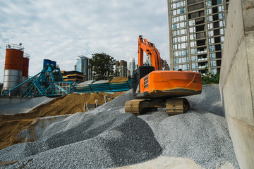 Large orange excavator working on a gravel on construction site. Details of industrial excavator. Big excavator standing on a hills of gravel and transporting it. Heavy industry.