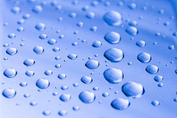 Drops of water on a blue metal surface. Abstract blue background made of water drops. Selective focus.