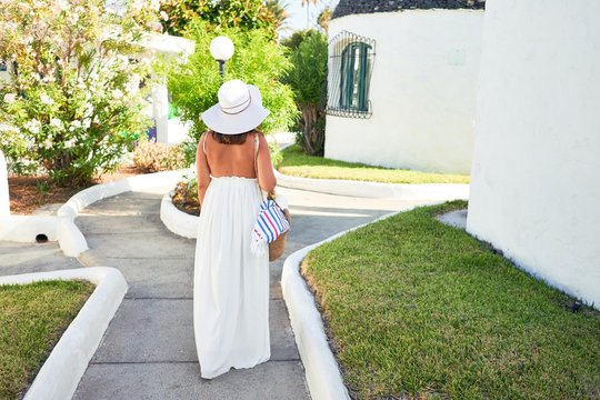 Young beautiful woman on white houses village walking on the streets on a sunny day of summer