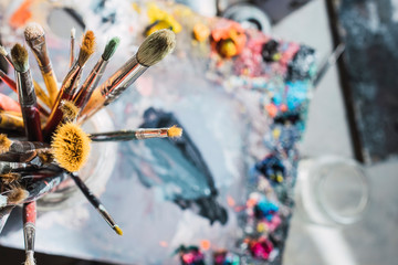 used and painted brushes on a palette of colours