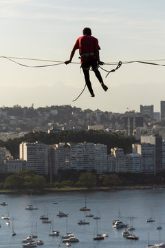 Slackliner walking on highline with ocean boats and city buildings