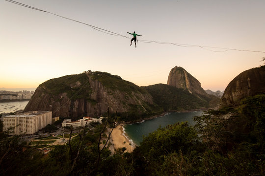 Slackliner sitting on highline on beautiful sunset near Sugar Loaf
