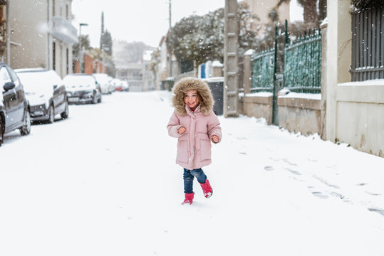 Young girl playing in street in snow in France facing camera