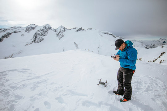 Man preparing to use drone on snow covered mountain.