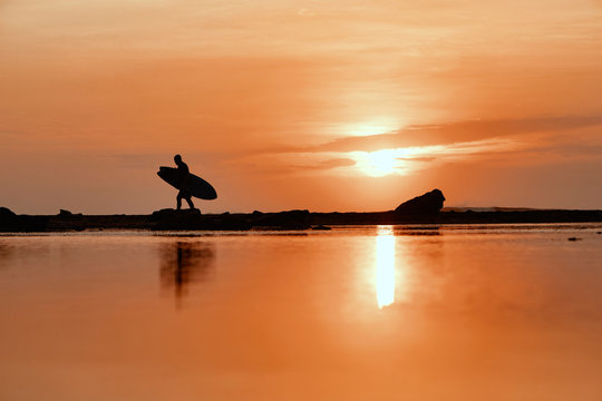 Silhouette of surfer at sunset on the beach