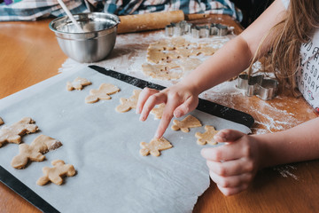 Young girl putting gingerbread man on baking tray
