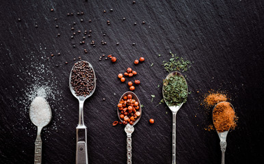 A selection of spices on vintage spoons on a slate chopping board