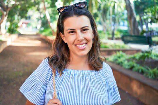 Young beatiful woman smiling happy and cheerful at green park on a sunny day of summer