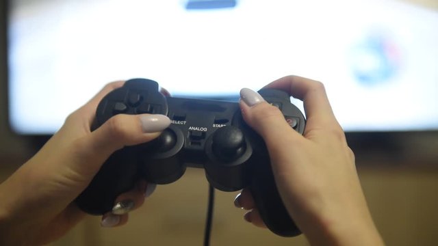 Girl hand holding game joystick. Close up of female hand playing video game with controller. Gamer press buttons on gamepad