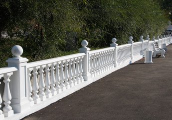 stone fence fence with balusters and a bench in front
