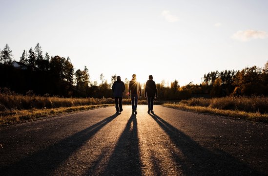 silhouette of family walking down a country road at sunset