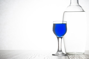 Glass bottle with vodka and a glass of blue cocktail