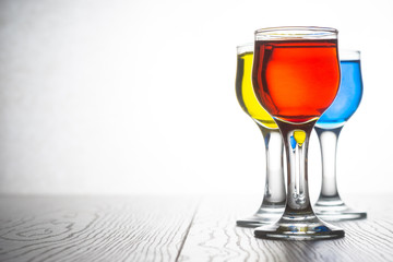 Glass piles with cocktails of red, blue and yellow color, side view