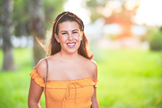 Young beautiful girl smiling happy and confident walking at the town street, standing with a smile on face at green park