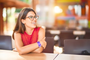 Young beautiful girl smiling happy and confident sitting on chair restaurant at the town park