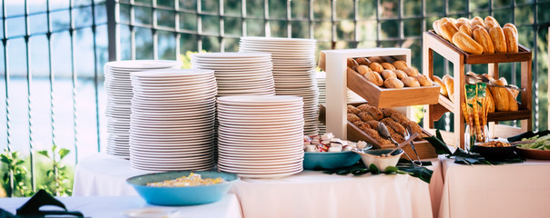 Table full of fresh bread and empty dishes ready for people enjoying the catering - party celebration food concept