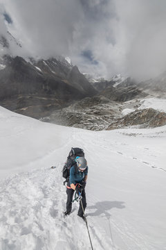 A woman climber practices ascending a rope on a steep snow slope