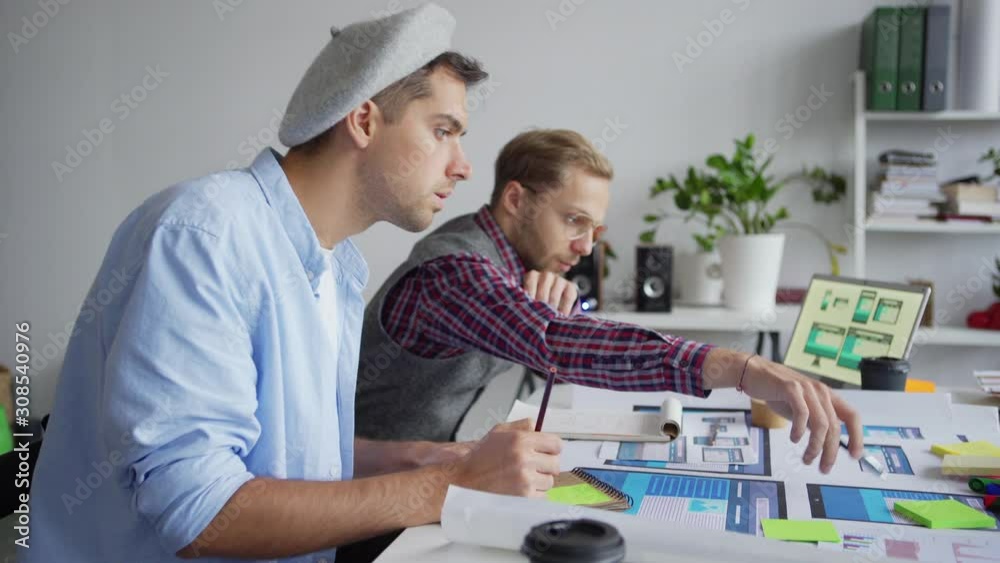 Wall mural panning shot of two web designers creating application interface for different devices. young profes