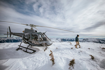 Helicopter pilot explores a snow-covered mountain summit.
