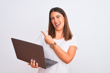 Beautiful young woman working using computer laptop over white background with a big smile on face, pointing with hand finger to the side looking at the camera.