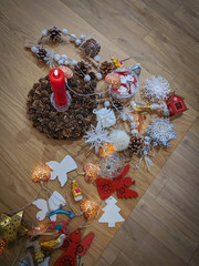 Christmas decorations (Santa clothespins, bumps, snowflakes, bird, bells) and burning red candle on a wooden background