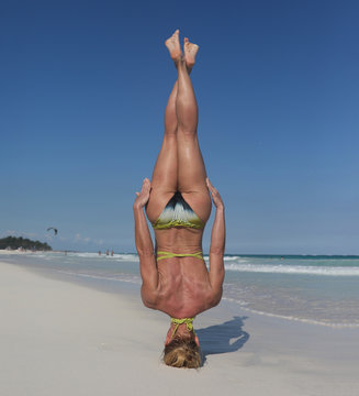 Woman doing headstand with no hands on beach
