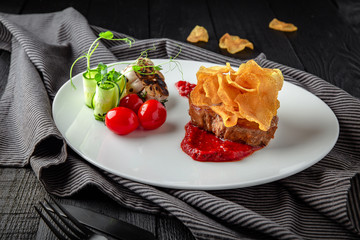 Beef steak mignon with spicy sauce, chips, vegetables. Restaurant menu. Background black boards.