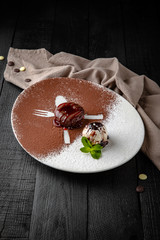 Chocolate fondant dessert with a scoop of ice cream. Restaurant menu. Background black boards.