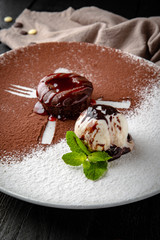 Chocolate fondant dessert with a scoop of ice cream. Restaurant menu. Background black boards.