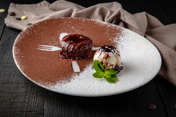 Chocolate fondant dessert with a scoop of ice cream. Restaurant menu. Background black boards.
