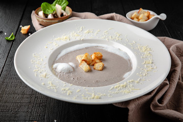 Cream of porcini mushroom soup. Liquid gourmet meal. Restaurant menu. Background black boards.