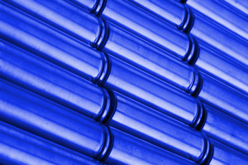 Angled view of blue metal parts with shiny steel cylindrical surface closeup. Abstract Industrial background with selective focus.