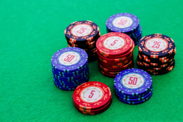 Stack of poker chips of different colors and value on a green table