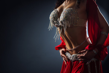 Beautiful belly dance of a girl in a red decorated ethnic dress in dark - obrazy, fototapety, plakaty