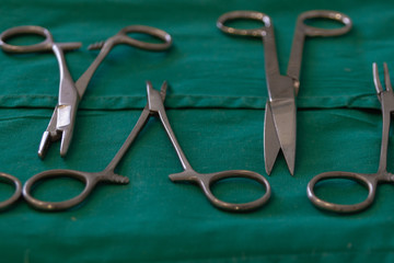 Surgical and medical equipment in the operating room. Sterile scissors, hemostat, needle holder on green background. picture taken with a shallow depth of field.