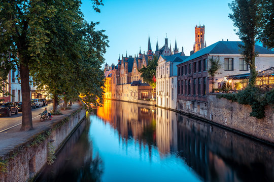A tranquil canal scene in Bruges, with the spires of the Stadhuis (Town Hall) in the distance, Bruges, Belgium