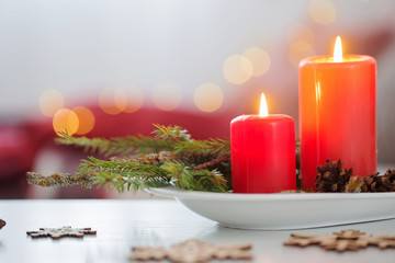 red burning candles on white table in living room