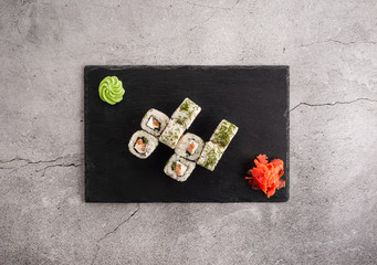 Obraz premium Japanese rolls with dill on a slate board, with wasabi and ginger