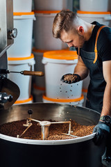 A worker near coffee roasting equipment will check time for testing the sample.