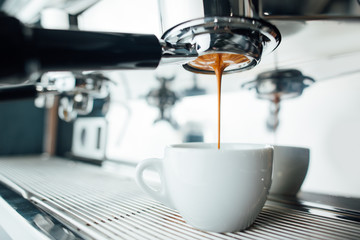 extraction of espresso from bottomless portafilter in white cup
