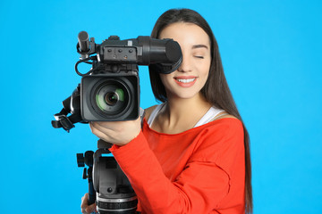 Operator with professional video camera on blue background