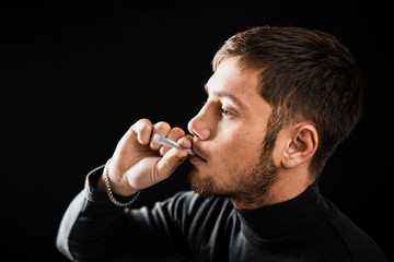 A man Smoking a cigarette rolled dollar in a tube, the concept of addiction, addiction and waste of money and money