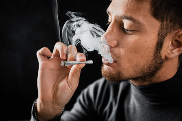 A man Smoking a cigarette rolled dollar in a tube, the concept of addiction, addiction and waste of...
