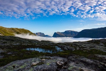 Fototapeta na wymiar Wonderful view of the top of the mountain on a background of blue sky and fog. Traveling in Norway