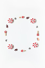 Simple Christmas composition. Round frame of clothespins, candy-bulbs, deer confetti and gifts on white background, copy space. Vertical. Minimal style. Top view. For social media, greeting card