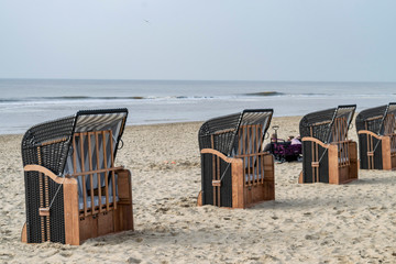 People chill out in the cold beach on the striped sun protective chair background. Seascape cold beach of the North Sea in Egmond aan Zee, Netherlands